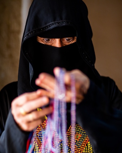 国家地理的的INS图片-(2017-12-13 15:51:22)Photo @tasneemalsultan 
Oaybidah Aludaini – known as Um Ahmed shows her handmade jewellery, that's inspired by Bedouin textiles “This work represents my roots, because I learnt this craft through my mother, aunts and grandmother who taught me how to weave with beads, as well as make tassels and macramé,” She has spent the last year alongside her daughter and granddaughter, to produce a contemporary range of beautifully crafted tasselled earrings and necklaces. A mother of nine children with close to 50 grandchildren, the master artisan proudly displays and sells her work at fairs across the Kingdom. She became her family’s main breadwinner after her husband passed away. Words by Alex Aubry #riyadh #saudiarabia #jewelry #handmadejewelry #torquoisemountain