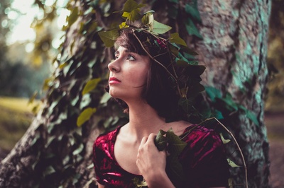人与植物的图片-站在树前的戴红色圆领帽袖上衣的女人