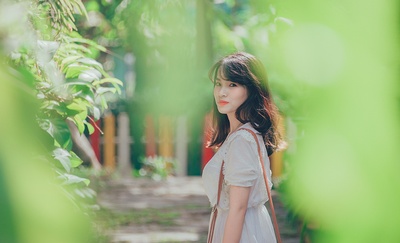 人与植物的图片-穿白色连衣裙带吊带包的女人