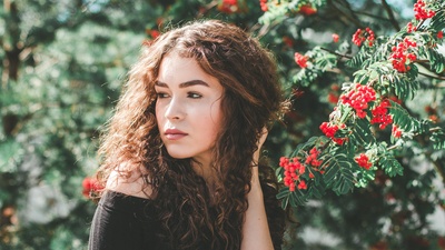 人与植物的图片-穿着黑色露肩衬衫的女人站在红花旁边