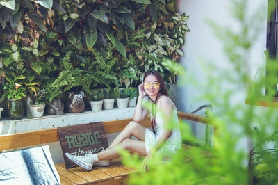 人与植物的图片-穿着白色背心的女人坐在棕色长椅上