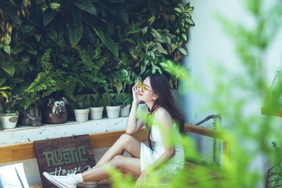 人与植物的图片-穿着白色无袖连衣裙坐在棕色木椅上的女人