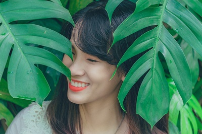 人与植物的图片-叶子边女孩的特写摄影