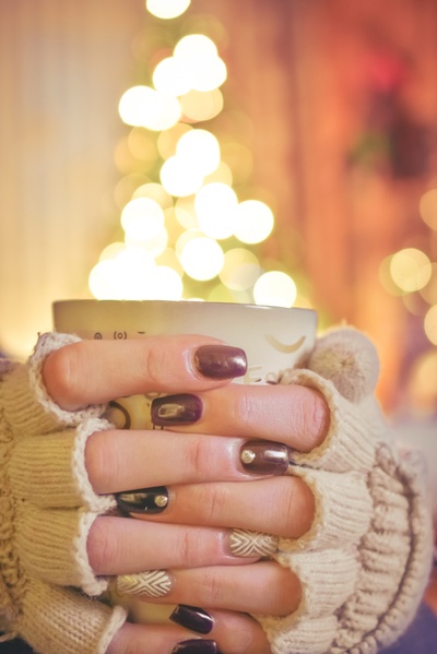 那种舒适的感觉的图片-在点燃的圣诞树前拿着杯子的人