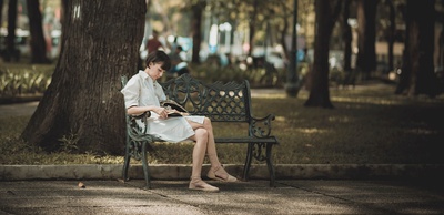 爱读书的图片-女人坐在公园的金属长椅上看书