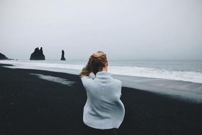 海景的图片-穿着毛衣站在海滩前的女人