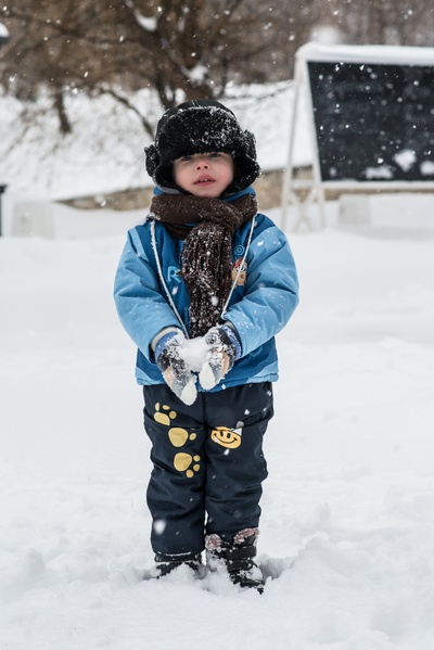 雪在下落的图片-蹒跚学步的孩子站在积雪的雪球上