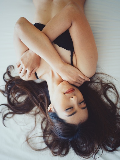 明亮的早晨的图片-靠在床上的女人