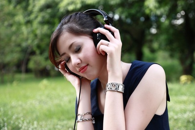 让音乐播放的图片-在户外拿着并戴着黑线耳机的女人