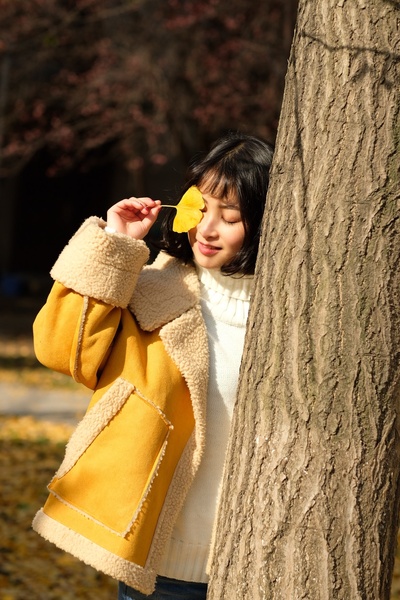 真实的人，真实的地方的图片-穿黄夹克拿黄叶的女人