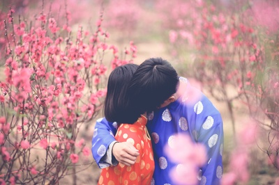 选择性聚焦的图片-穿橙色衣服的拥抱男人的女孩