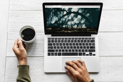 企业家生活的图片-拿着MacBook Pro和白色杯子的人