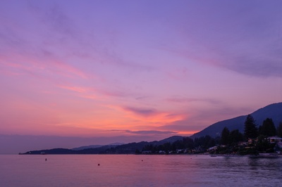 紫色的图片-紫色的夕阳反射出平静的沿海水域