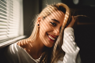 人的图片-选择性聚焦摄影，微笑的女人拿着她的头发在百叶窗旁边